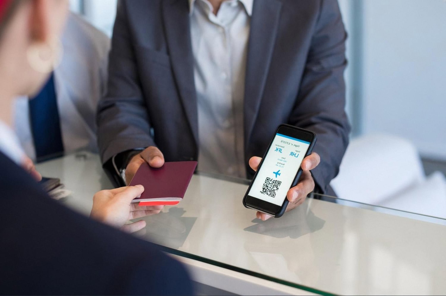 Guest showing a QR code on a smartphone at a hotel front desk for mobile check-in