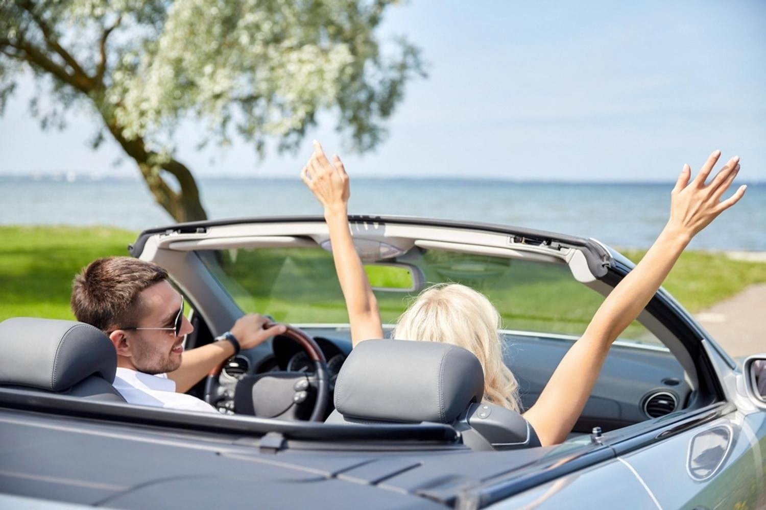 Couple enjoying a convertible car hired in the UAE with the sea in the background
