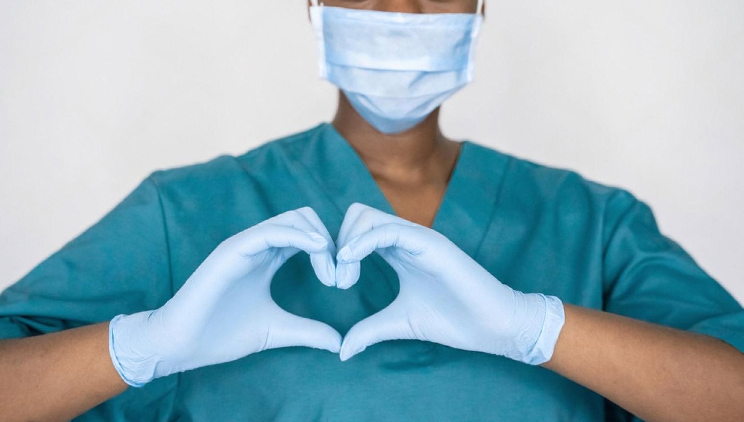 Healthcare worker in scrubs and gloves forming a heart, symbolising medical coverage in the UAE