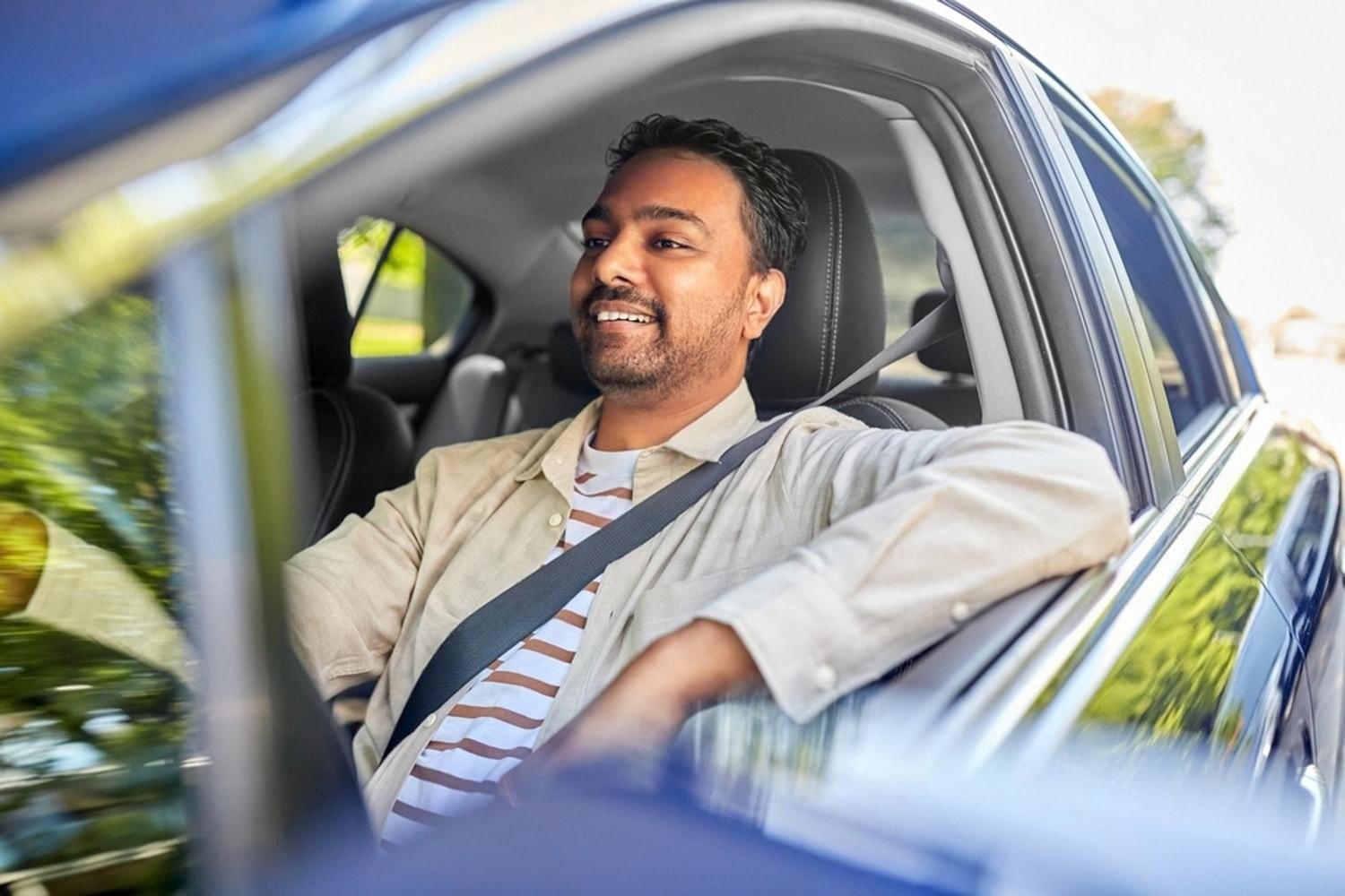 Smiling driver behind the wheel of a rented car in Dubai